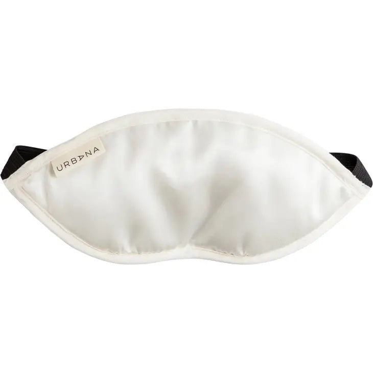 A white silk eye pillow with a black elastic band, ideal for sleep or relaxation, featuring the word "URBANA" on a small tag stitched on the upper left side of the mask. This elegant detail evokes the tranquility of French lavender, perfectly captured in the LAVENDER SILK EYE PILLOW by EUROPEAN SOAPS, LLC.