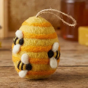 BUSY BEE HIVE ORNAMENT made of egg-shaped colourful wool felt with yellow and orange stripes, decorated with three small bees and featuring a jute twine loop for hanging.