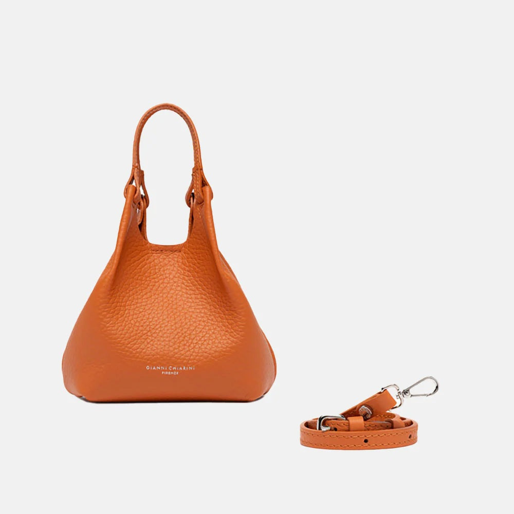 The GIANNI CHIARINI MINI DUA BAG IN SPICE, a small textured orange leather bag with double handles, is shown on a white background alongside its matching detachable crossbody strap with silver clasp.