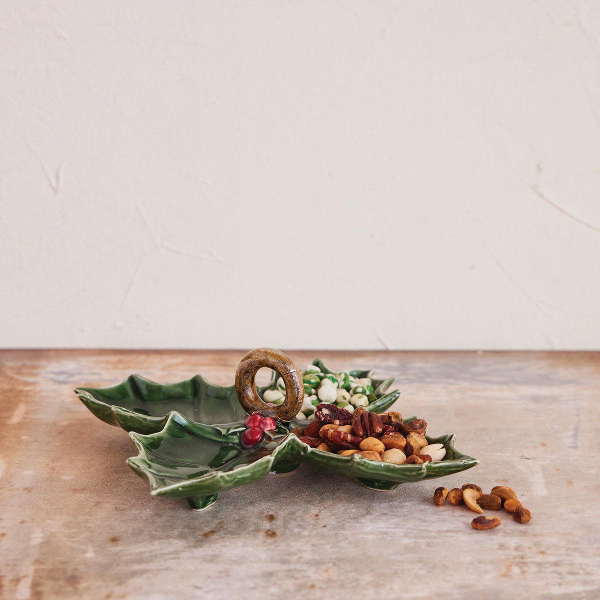 Two green CREATIVE COOP CERAMIC HOLLY LEAF SHAPED DISH serving platters, one with three sections and one with four, each featuring a central dark ring handle and red berries.