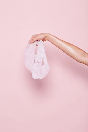 A carton labeled "ESW BEAUTY - BLUEBERRY COCONUT MILK MASK" by ESW BEAUTY sits among a milk bottle, blueberries, coconuts, and coconut flakes on white—perfect inspiration for a blueberry coconut plant-based sheet mask.