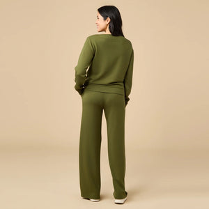 A woman wears a SOFTIES - DREAMTECH BOAT NECK WITH PINTUCK PANT SET in olive green, featuring a long-sleeve boat neck top and matching wide-leg pintuck pants.