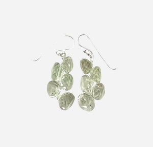 The ANN LIGHTFOOT - FACETED ONION CUT GREEN QUARTZ DROP EARRINGS feature dangling faceted gemstones in clusters. Each earring has five oval stones, including onion-cut green quartz, hanging elegantly from sterling silver hooks on a plain white backdrop.