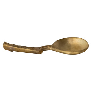 A fish-shaped serveware dish with green olives, a small bowl of bread and cheese pieces, and the CREATIVE COOP BRASS SPOON WITH TWIG SHAPED HANDLE holding an olive, all displayed on a textured white surface.
