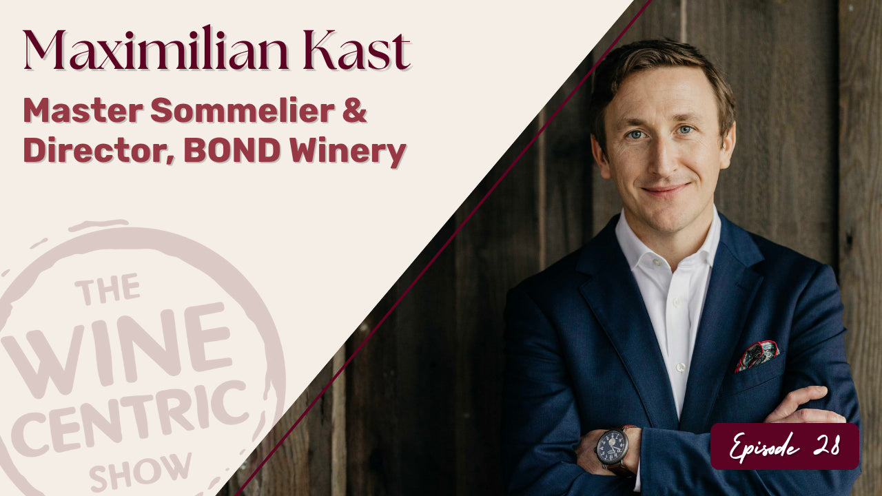A man in a navy suit stands smiling with arms crossed against a wooden wall. Text reads, “Maximilian Kast, Master Sommelier & Director, BOND Winery” and “The Wine Centric Show, Episode 28.”.