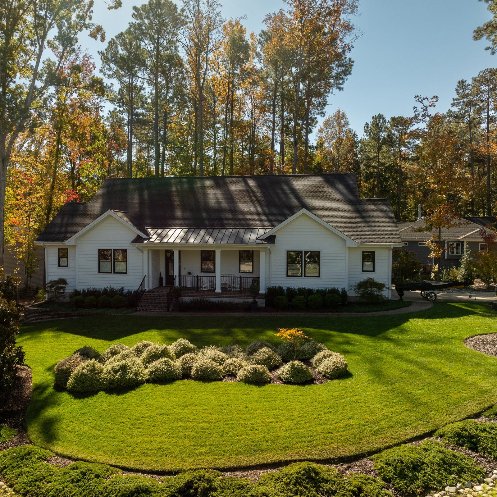 White house with black roof surrounded by trees with autumn foliage