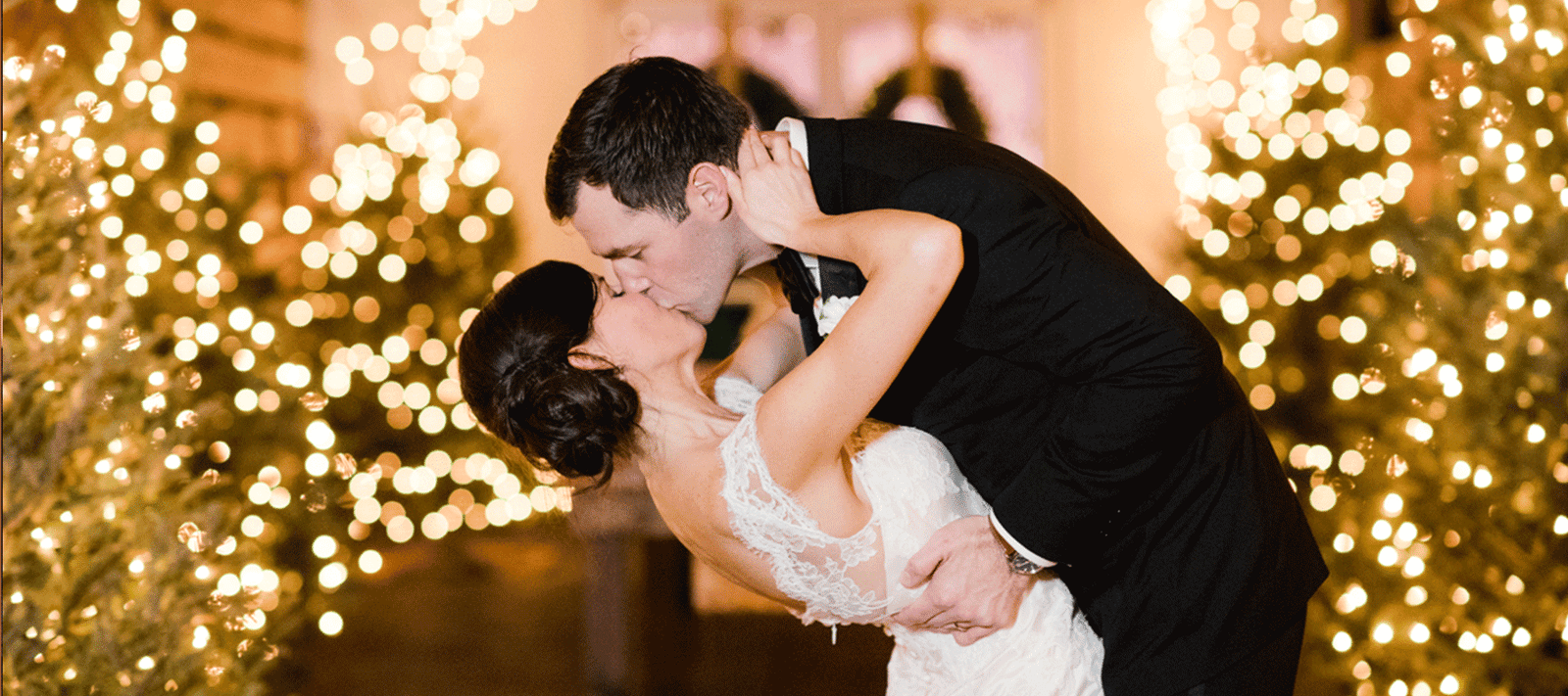 Couple embracing in front of a Christmas tree with lights