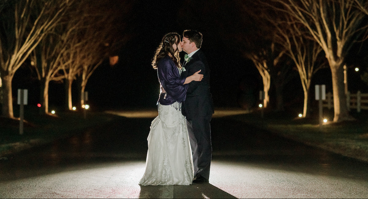 Couple embracing under a canopy of trees at night.