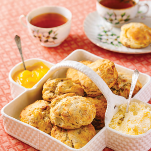 Person standing on a porch in front of a light blue house with a white door.