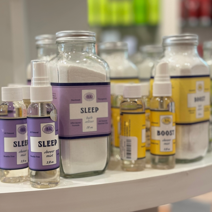 A display of glass bottles and jars with purple and yellow labels, including products labeled 