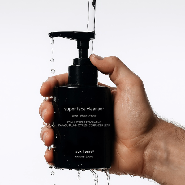 A hand holds a wet black bottle of 