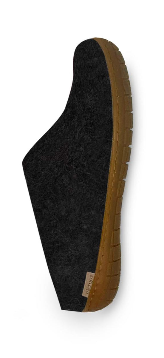 A single black slipper with a brown, textured rubber sole, viewed from the side against a white background. The slipper has a soft, felt-like upper material and a small fabric tag near the heel.