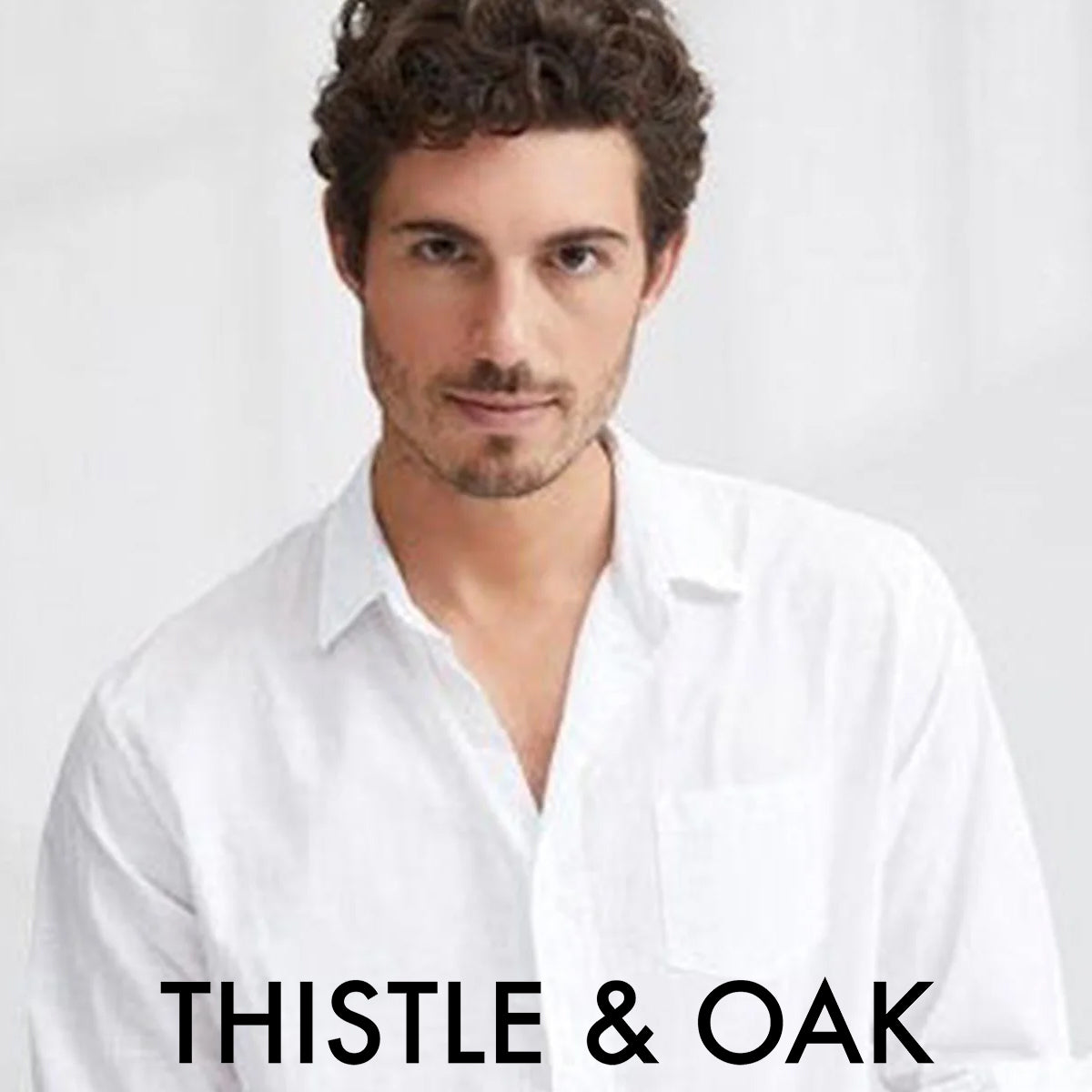 A man with curly brown hair and light stubble wears a white button-up shirt, looking at the camera. The background is light and plain. The text "THISTLE & OAK" appears at the bottom of the image.