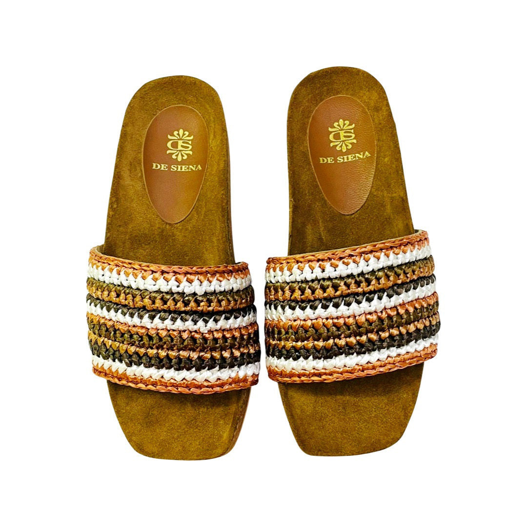 A pair of DA SIENA - LUCILLA RAFIA SLIDE sandals by DE SIENA features tan-colored soles with a raffia knotted top, adorned with multicolored stripes in shades of green, blue, brown, and yellow. The eco-style footbed is tan and showcases the brand's name and logo printed in gold, making it perfect for your summer style.