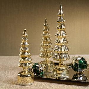 The ZODAX ALPINE ROTATING LED TREE IN ANTIQUE GOLD - SHORT is a small, stylized Christmas tree ornament with tiered branches, a glass LED light, and a rounded base, shown upright against a white background.