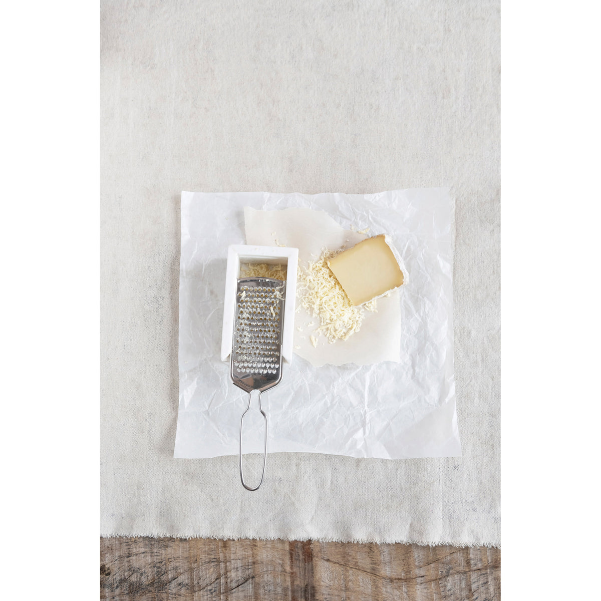 The CREATIVE COOP MARBLE AND STAINLESS STEEL GRATER, with its sleek handle and white marble rest, is shown from above, making it a stylish and modern addition to any kitchen countertop.