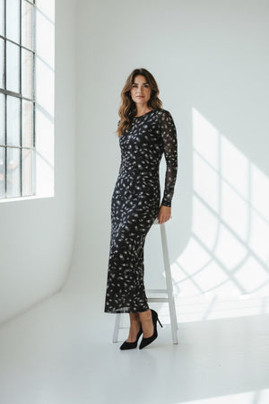 The FRANCO FERRARI BALLET MESH MAXI DRESS is a long-sleeved, ankle-length black stretch mesh dress with a sheer overlay featuring scattered gray and white abstract patterns, shown against a white background.