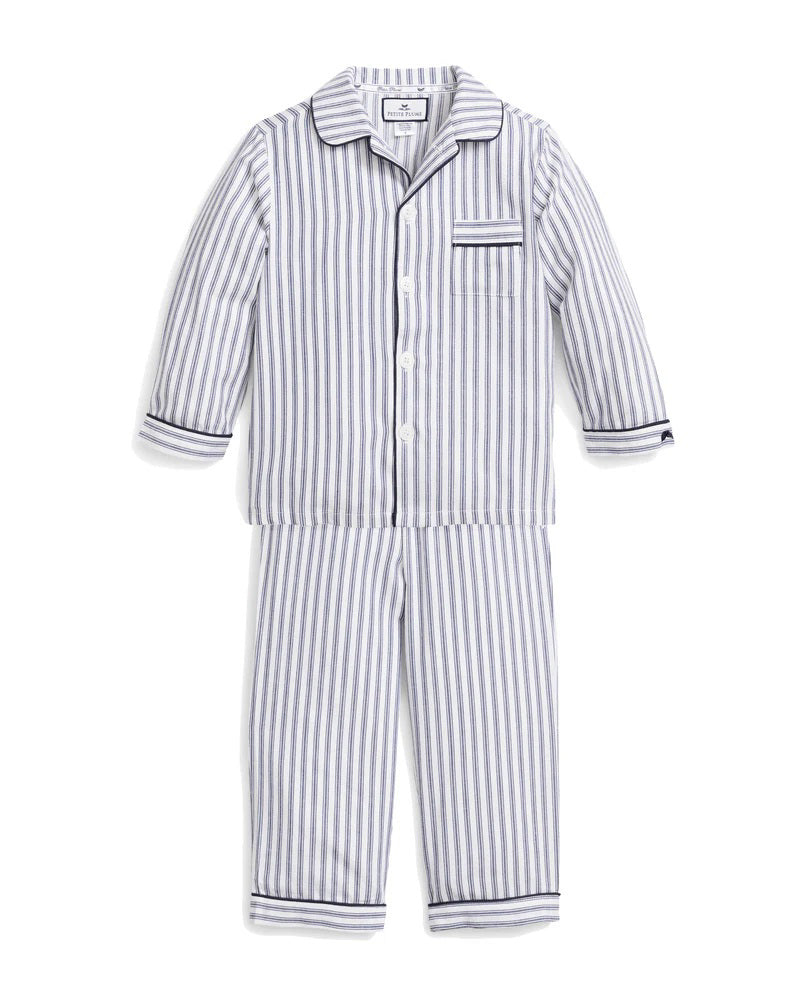The PETITE PLUME FEARRINGTON LIFESTYLE COLLECTION - CHILDREN&#39;S TWILL NAVY FRENCH TICKING PAJAMA SET is a delightful option for kids, featuring long sleeves and pants with chic vertical white and gray stripes. This set is crafted from yarn-dyed cotton, boasting a top with a collar, full button-down front, and a single chest pocket adorned with matching fabric piping along the cuffs and pocket opening.
