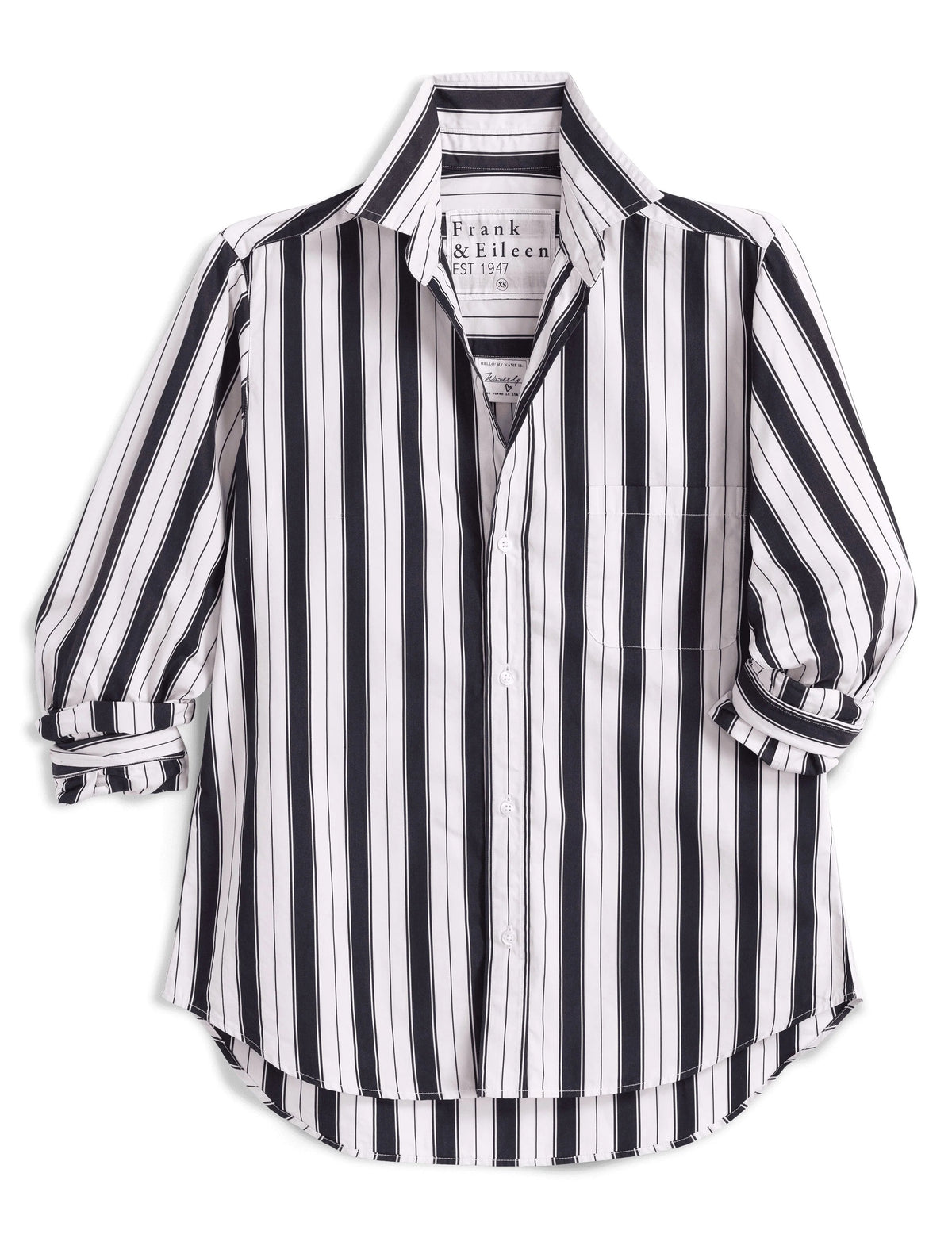 A woman stands outdoors in the sunlight, wearing the FRANK & EILEEN Waverly NYC Button Up Shirt in Italian Brushed Superluxe Cotton with black and tan stripes. The shirt features rolled-up sleeves, and she is buttoning or unbuttoning its perfectly tailored fit.