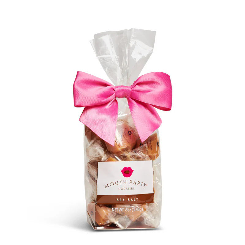 A clear bag of Mouth Party Sea Salt Caramels, tied with a bright pink bow and labeled &quot;MOUTH PARTY - SEA SALT CARAMEL BAG.