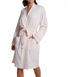 A person wearing the P. JAMAS - BUTTERKNIT SHORT ROBE by FASHIONVIEWS, made of silky light blue fabric with a tied belt. The robe features long sleeves, two pockets near the waist, and a design reminiscent of a kimono style. The individual is standing against a plain white background, with their head not visible.