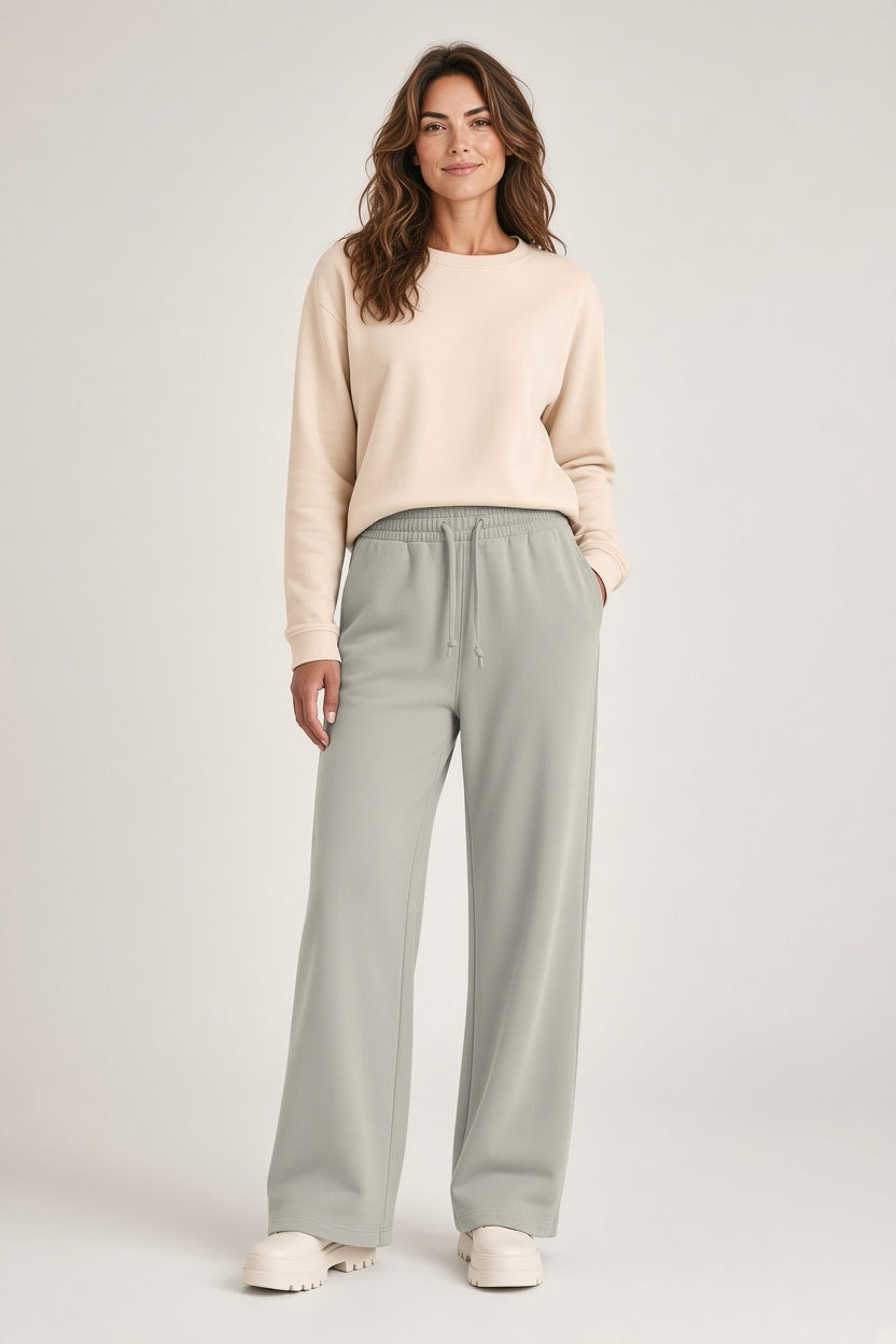 A woman wearing a beige long-sleeve crewneck sweater and SAVE THE DUCK - IZUMI PULL ON DRAWSTRING WIDE LEG PANT IN RAINY BEIGE with white platform shoes.