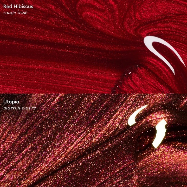 A hand with shiny, iridescent red nails holds a matching bottle labeled “MANUCURIST - GREEN™ NAIL POLISH IN RED HIBISCUS” by MANUCURIST INC against brown skin. This luxurious vegan, cruelty-free nail polish delivers vibrant color and a flawless finish.