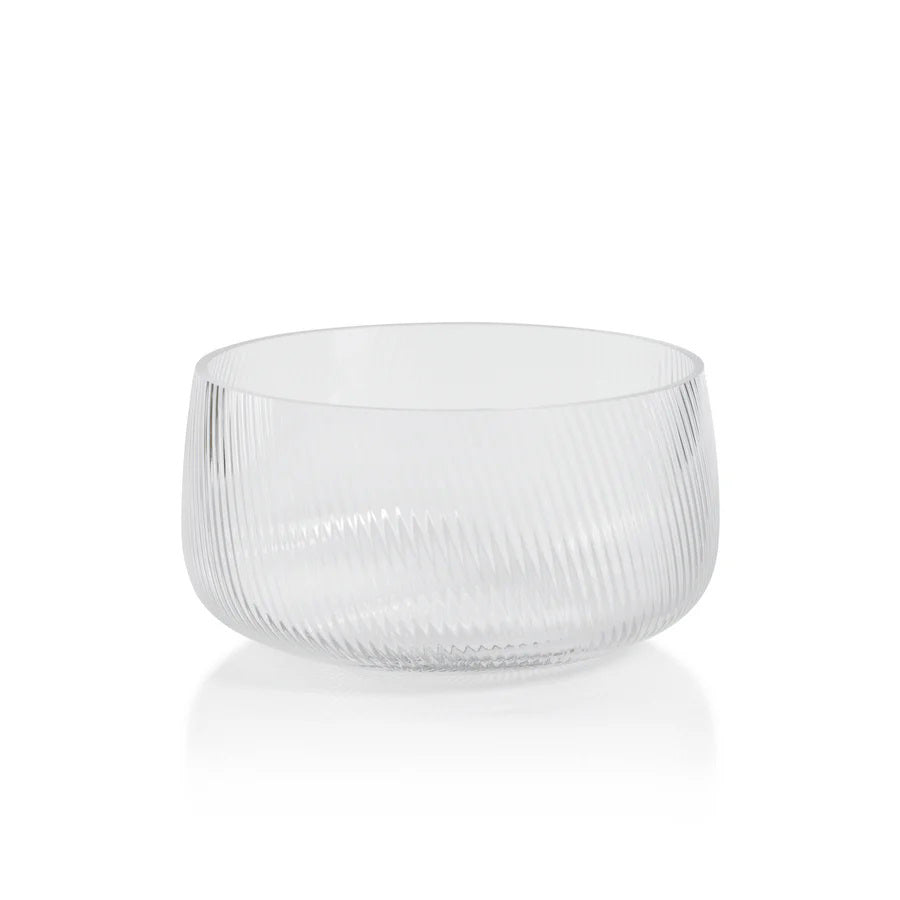 The CONNAUGHT RIPPLED GLASS BOWL - MEDIUM by ZODAX is a transparent, round glass bowl featuring a smooth rim and an elegant, diagonal ribbed texture on its surface. Measuring 21.59 cm x 10.8 cm (8.5 in x 4.25 in), this bowl is showcased against a plain white background, emphasizing its refined simplicity.
