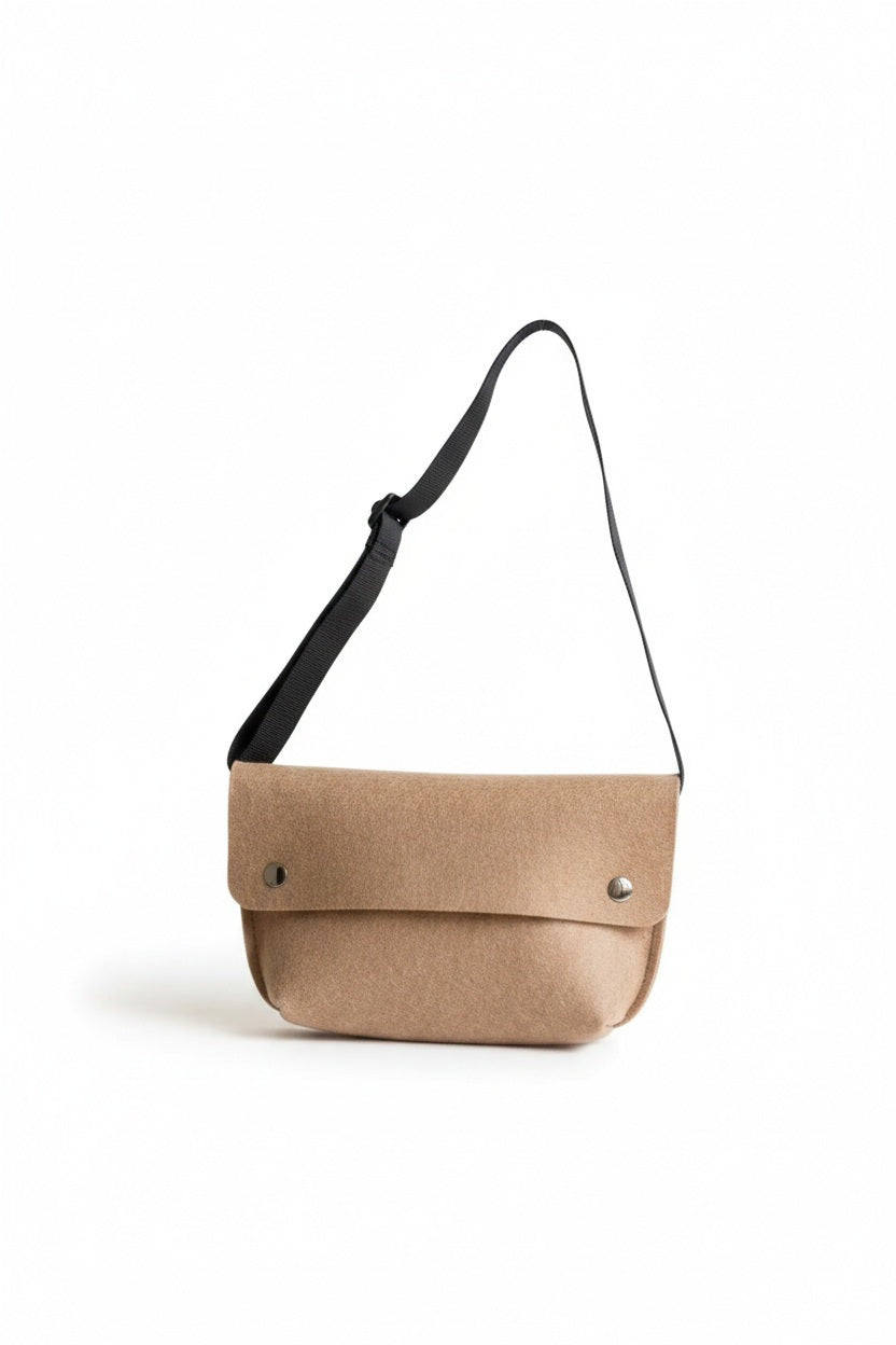 The WOOLBERRY - FELTED WOOL BELT BAG by WOOLBERRY is a small green belt bag crafted from felted wool, featuring a flap secured by two silver snap buttons, and is displayed against a white background.
