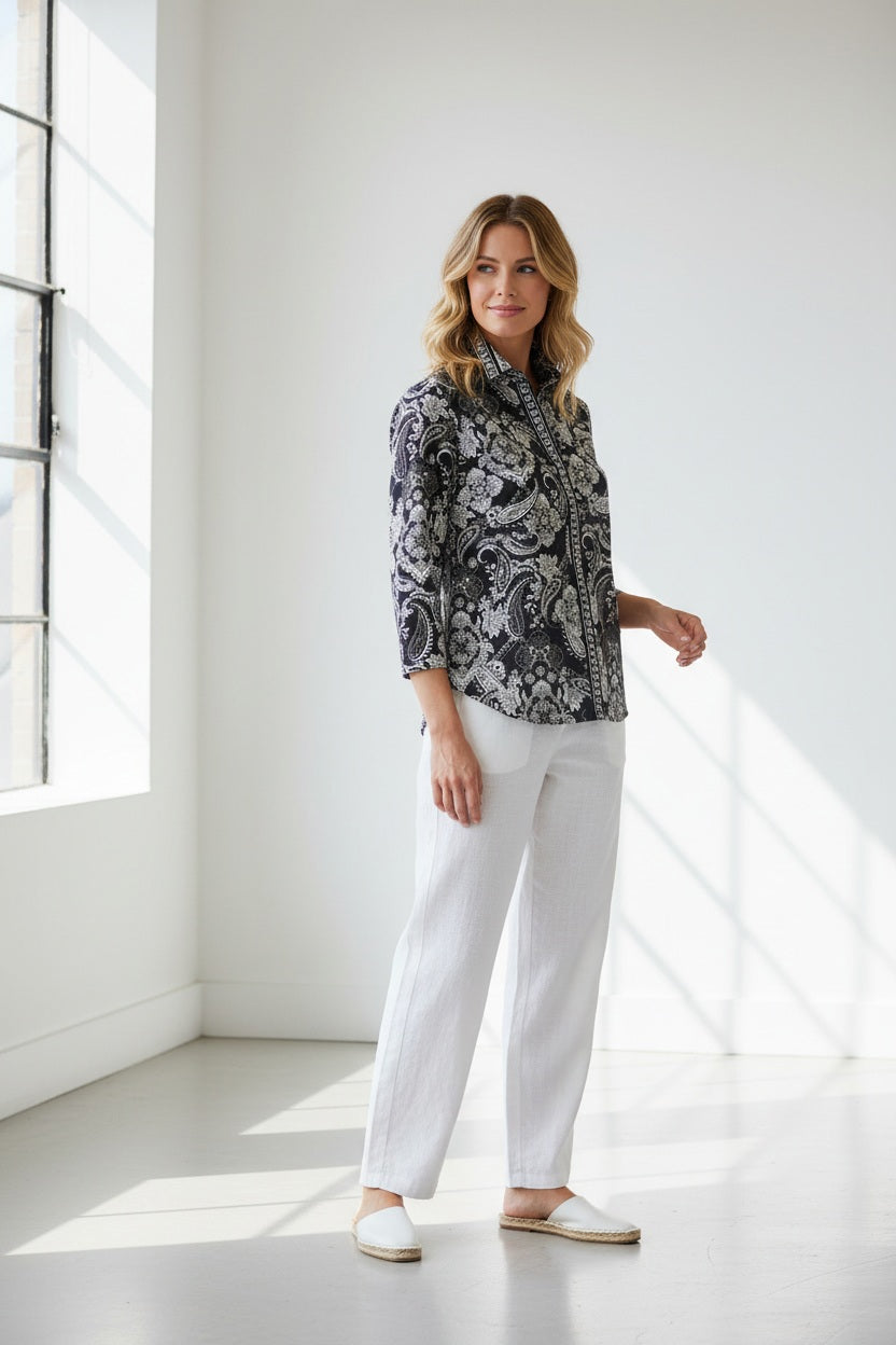 A woman wearing the HINSON WU Lizette 3/4 Sleeve Paisley Print Shirt—a black and white paisley-patterned cotton shirt with a collar—paired with white pants, stands against a plain light background.