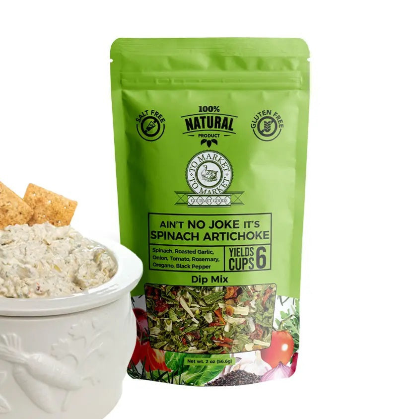 A green bag of TO MARKET - SPINACH ARTICHOKE DIP MIX from TO MARKET- DIPS &amp; SPREADS stands behind a white bowl filled with spinach artichoke dip and crackers. Made with roasted garlic and natural ingredients, this gluten free mix makes six cups.