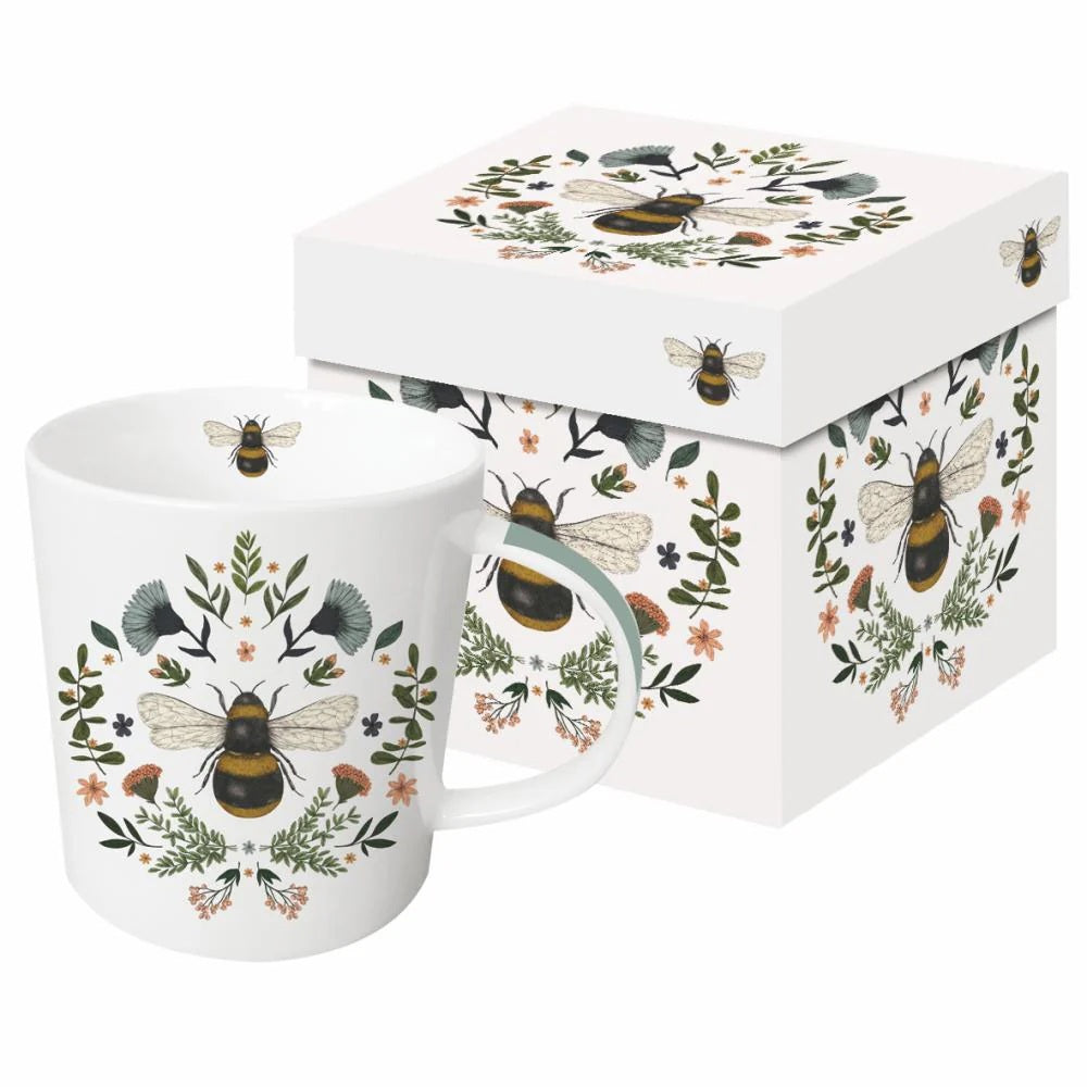 The SECRET BEE MUG by PAPER PRODUCTS DESIGN is a white bone china mug with a matching box, adorned with symmetrical illustrations of bees, green leaves, and small orange flowers—a delightful gift for any nature lover.