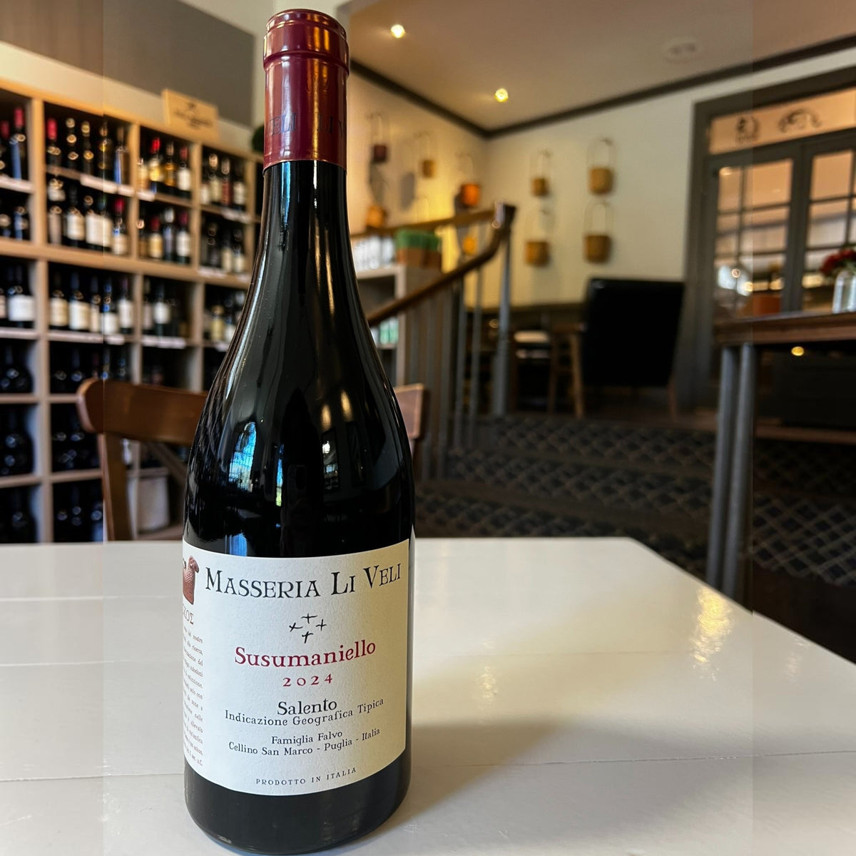 A bottle of MASSERIA LI VELI SUSUMANIELLO 2023 by WINEBOW, crafted from distinguished Puglian grape varieties, with a red foil top and a cream-colored label featuring black and red text, set against a plain white background.