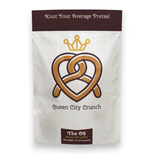 A white and brown bag of QUEEN CITY CRUNCH - OG features a gold heart-shaped pretzel with a crown and the phrases "Knot Your Average Pretzel" and "The OG, savory with a kick." Brand: QUEEN CITY CRUNCH.