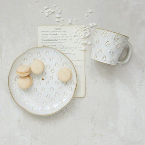 A DEBOSSED PLATE WITH GOLD ELECTROPLATING and matching mug with a reactive glaze and debossed gold Christmas tree patterns, containing macarons and marshmallows next to a printed holiday program.
