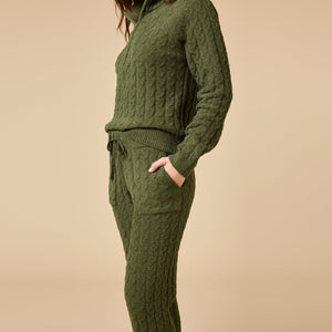 A woman wearing a marshmallow-soft, cream-colored SOFTIES - CABLE KNIT MARSHMALLOW ½ ZIP WITH TAPERED PANT SET, featuring a half-zip pullover and matching pants with a drawstring waist.