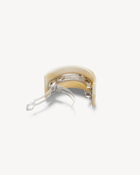 A person with straight brown hair tied back with the MACHETE French Pony Barrette in Alabaster, wearing gold hoop earrings and a black top, is shown from behind against a plain light background.