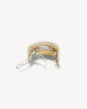A person with straight brown hair tied back with the MACHETE French Pony Barrette in Alabaster, wearing gold hoop earrings and a black top, is shown from behind against a plain light background.