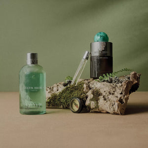 A green bottle of MOLTON BROWN Wild Mint and Lavandin Bath & Shower Gel with a silver cap, featuring a crisp white label, is displayed on a plain white background.