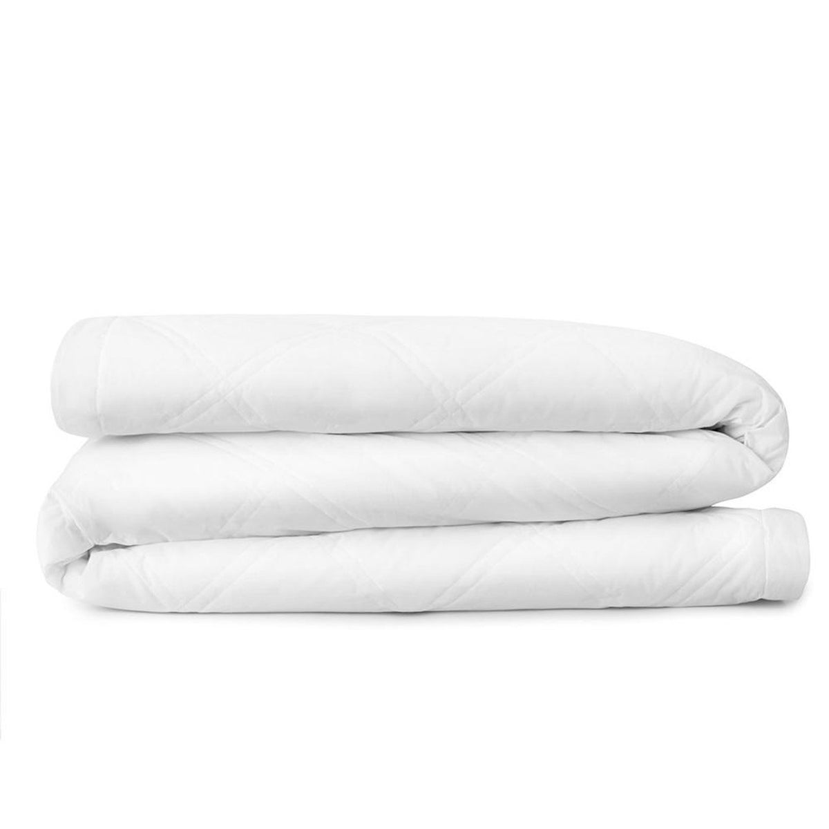 A well-made bed with a tufted headboard features the Downlite Fearrington Lifestyle Bedding Collection&#39;s Smartdown Lightweight Feather Mix Blanket, complemented by crisp white bedding and matching pillows. Two black bedside tables, each adorned with tall white lamps, stand on either side of the bed. A gray cushioned bench is positioned at the foot of the bed, and large windows with sheer curtains allow plenty of natural light to illuminate the room.