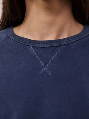 A person with long, straight hair is wearing the HARTFORD - LIGHT FLEECE SWEATSHIRT IN NAVY by HARTFORD and light-colored pants, standing with one hand in their pocket against a plain white background.