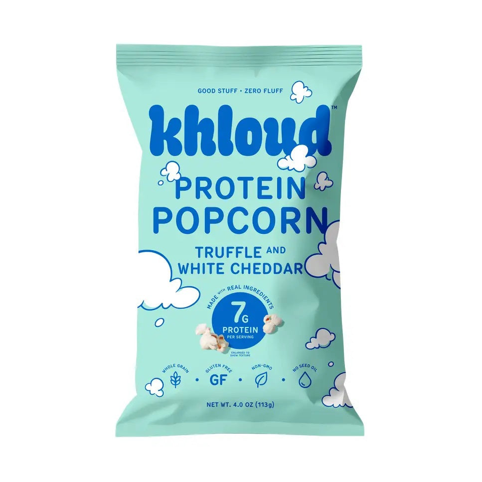 A light blue bag of KHLOUD FOODS’ KHLOUD- TRUFFLE & WHITE CHEDDAR PROTEIN POPCORN, featuring playful cloud designs on the packaging, delivers 7g of protein per serving and is gluten-free. This delicious snack combines the rich taste of truffle with classic white cheddar for a guilt-free popcorn experience.
