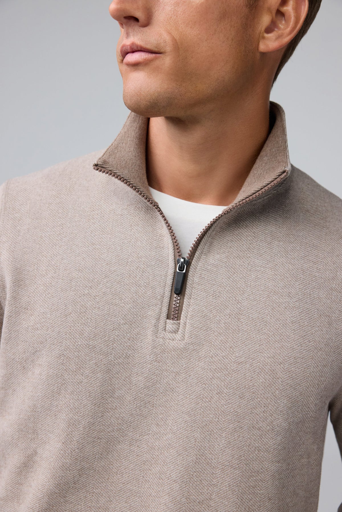A man wearing a tan Mack Weldon ACE QUARTER ZIP French terry pullover with ribbed cuffs and hem.