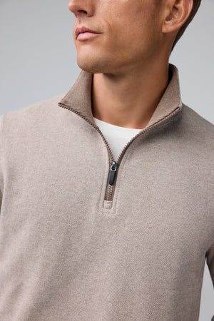 A man wearing a tan Mack Weldon ACE QUARTER ZIP French terry pullover with ribbed cuffs and hem.