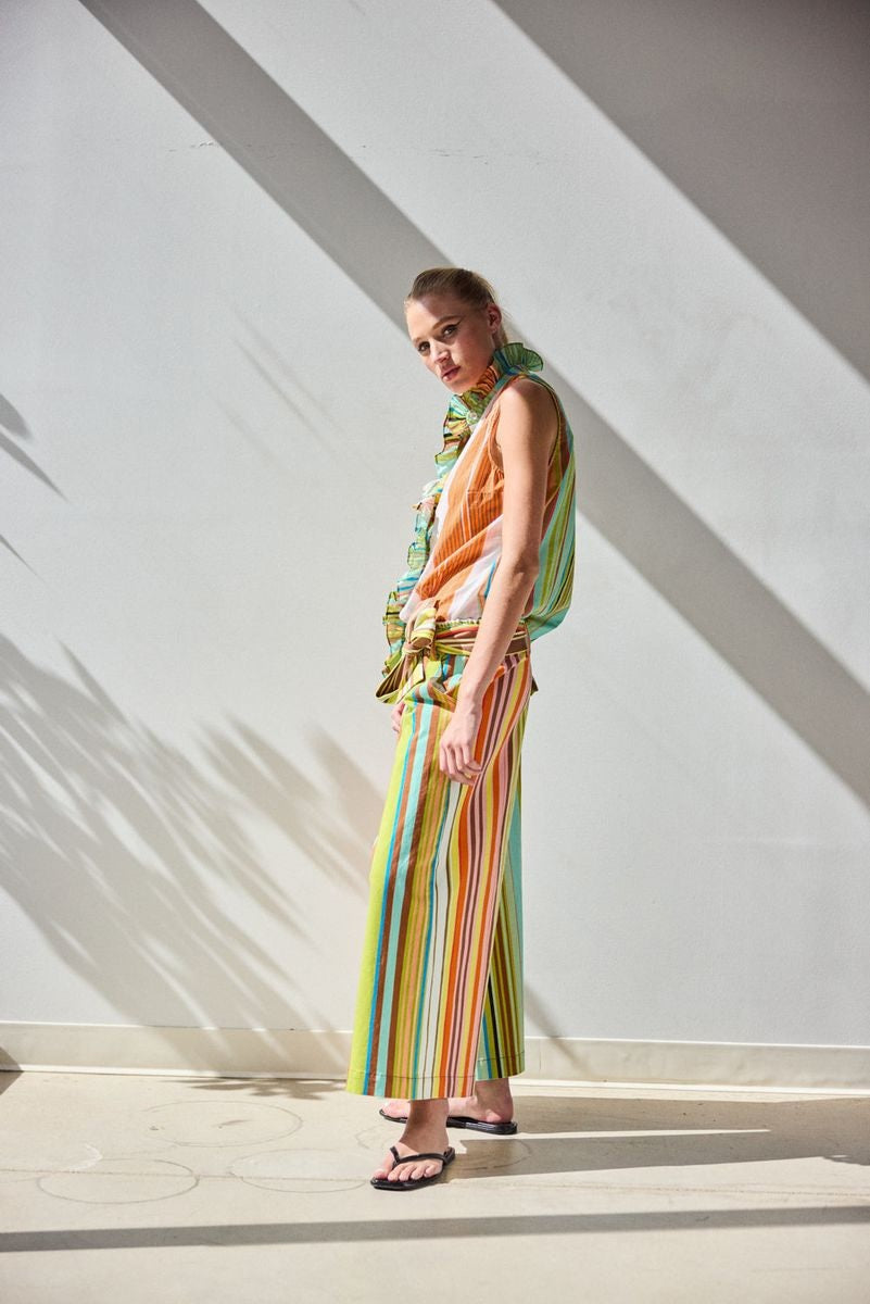 A person, seen from the back with hands on hips, wears the HOPE FOR FLOWERS - CROPPED PANT IN COMBO STRIPES: a colorful, striped matching set featuring wide leg cropped pants by HOPE FOR FLOWERS.