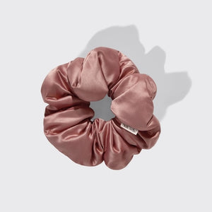 The KITSCH - PILLOW SATIN SCRUNCHIES IN BLUSH by KITSCH, shown in a circular arrangement with a subtle fabric tag on a light gray background, provide frizz control as a gentle, damage-free hair accessory.
