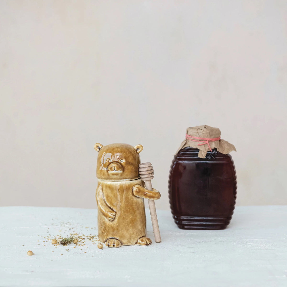 The CREATIVE COOP HONEY JAR WITH WOOD HONEY DIPPER is a ceramic, bear-shaped jar with a glossy brown finish, shown on a white background.
