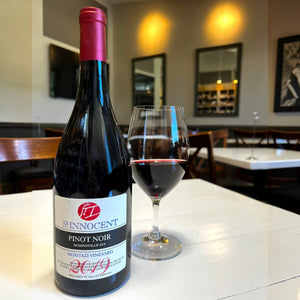 A bottle of ST. INNOCENT ‘MOMTAZI’ PINOT NOIR 2019 from WINE: WINEBOW, made with biodynamic grapes sourced from the acclaimed Momtazi Vineyard. The bottle features a red foil top and a cream label bearing the vineyard name, vintage year, and additional details. It is photographed against a white background.