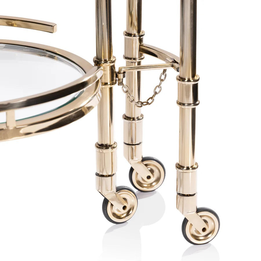 The SPIGA GOLD BAR CART by ZODAX features a vintage Italian-inspired design with elegant gold framing, mirrored glass shelves on both tiers, and smooth-rolling four-wheel mobility. Displayed against a white background, this piece is both stylish and functional.