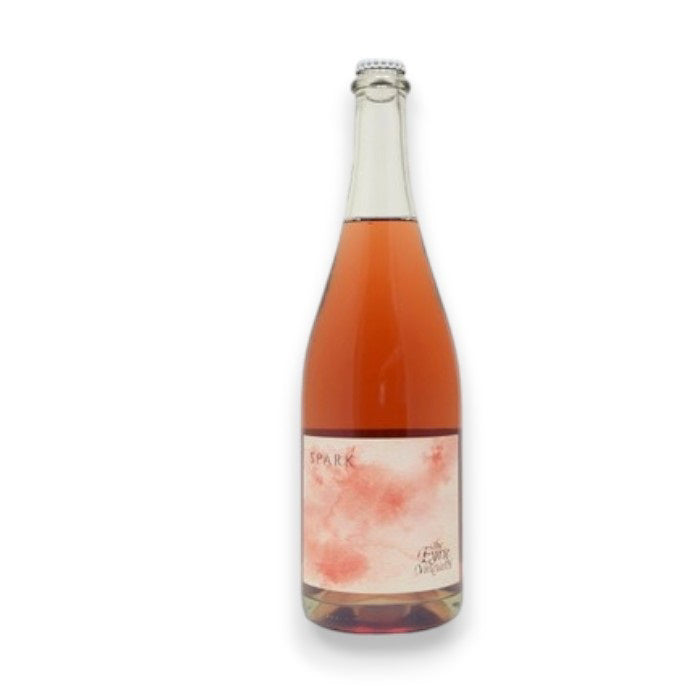 Originating from Oregon's Willamette Valley, the EYRIE 'SPARK' SPARKLING ROSÉ by WINE: ADVINTAGE is an orange sparkly wine made from Pinot Noir. It features a light cream-colored label with abstract red patterns and "Spark" in bold, topped with a silver cap against a plain white background.
